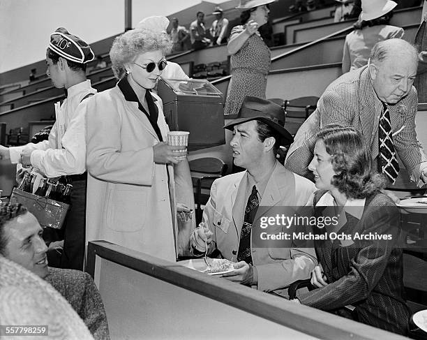 Actress Ann Sothern talks with actor Robert Taylor and actress Barbara Stanwyck during a tennis match in Los Angeles, California.