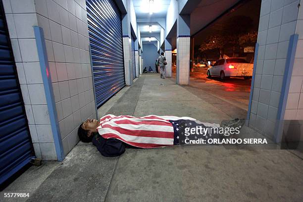 Un indigente duerme arropado con la bandera de los Estados Unidos sobre la acera de un negocio en el centro civico de Ciudad de Guatemala el 26 de...