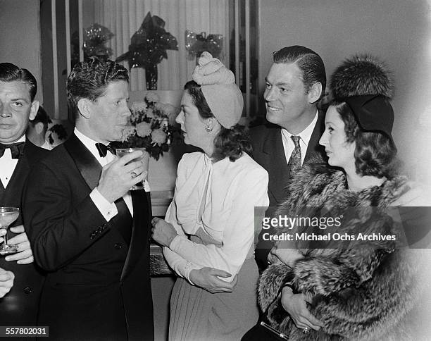 Actress Rosalind Russell talks with singer Rudy Vallee and actor Johnny Weismuller during a party in Los Angeles, California.