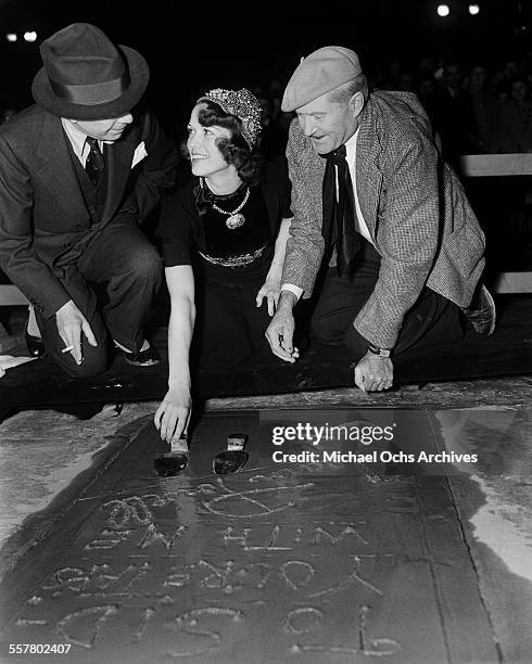 Actress Eleanor Powell has her shoe prints added to cement in front of Grauman's Chinese Theatre with the help of Sid Grauman and Jean W. Klossner in...