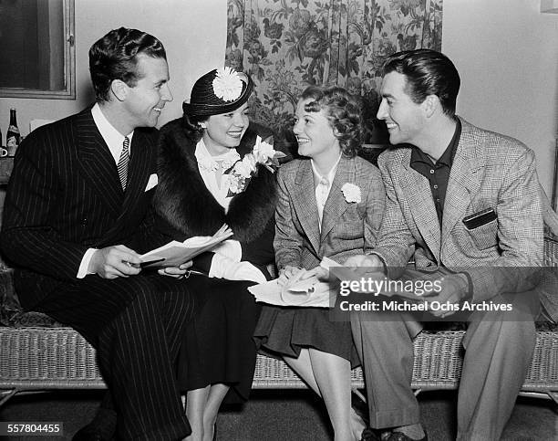 Actor Dick Powell talks with actress Frances Langford, actress Janet Gaynor and actor Robert Taylor in Los Angeles, California.