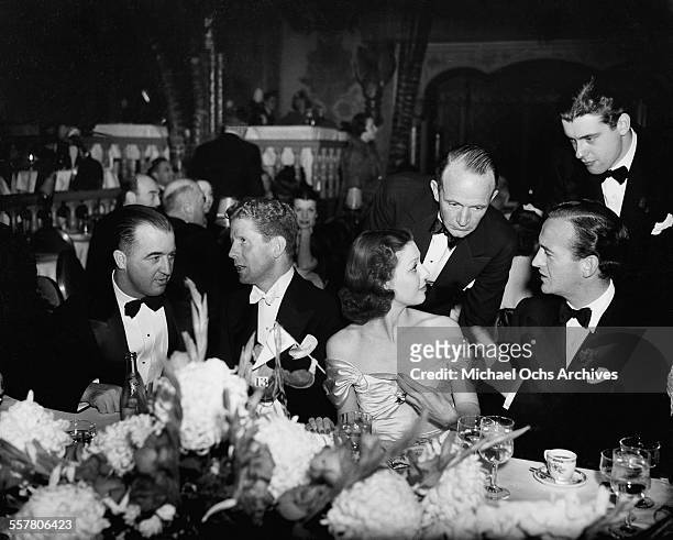 Singer Rudy Vallee sits with actress Loretta Young and actors David Niven and Richard Greene during an event in Los Angeles, California.