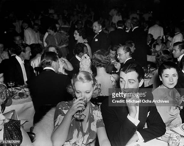 Actor Robert Taylor sits with actress Virginia Bruce during an event in Los Angeles, California.