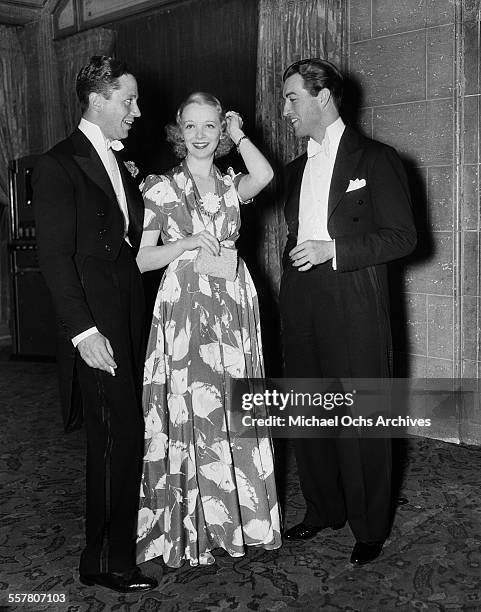 Actor Robert Taylor poses with actress Virginia Bruce and her husband screen writer J. Walter Ruben at an event in Los Angeles, California.