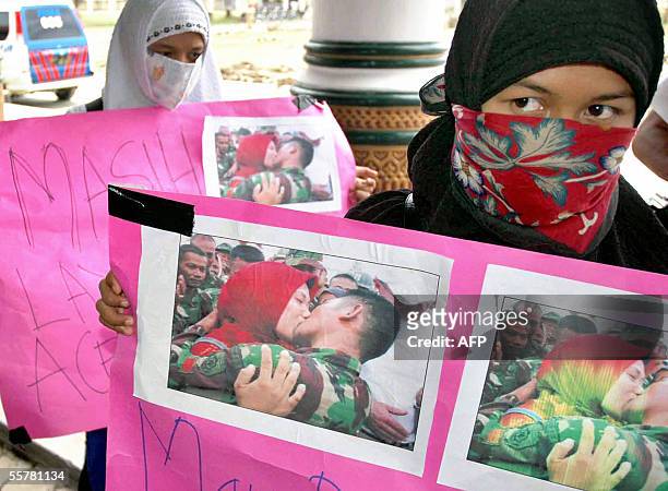 Indonesian women hold placards featuring pictures of a soldier kissing his girlfriend during a demonstration in Banda Aceh, 27 September 2005. Dozens...