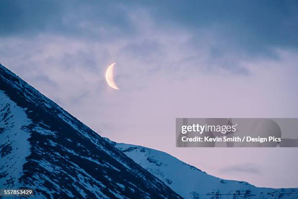 the crescent moon sets above the sentinal range along the alaska highway, muncho lake provincial park, northern canadian rockies - alcan highway stock pictures, royalty-free photos & images