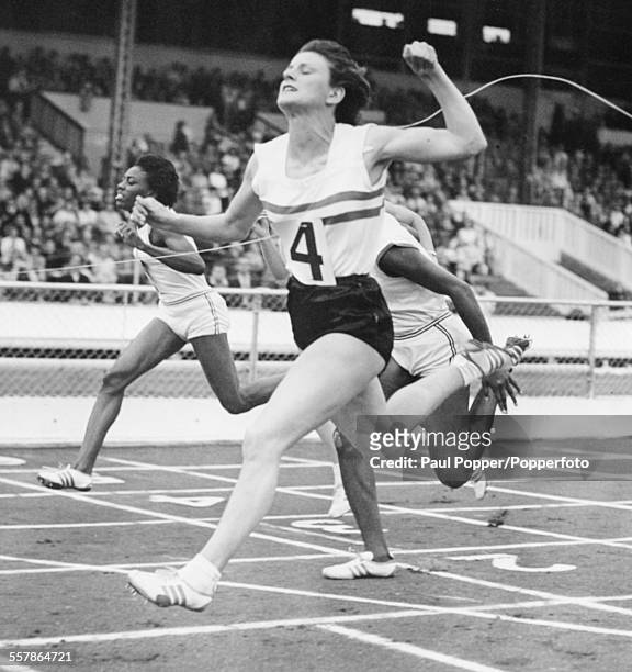 British athlete Dorothy Hyman crosses the finish line to win the 100 yard sprint during a US verses UK track and field meet at White City Stadium,...