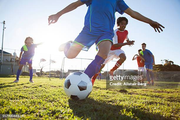 close up of boy kicking soccer ball - sportbegriff stock-fotos und bilder