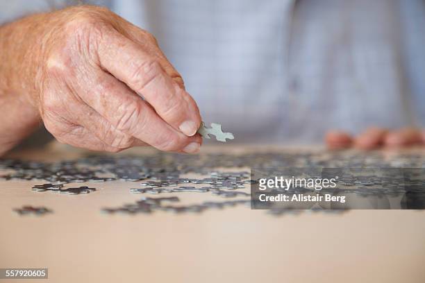 elderly man doing jigsaw puzzle - demência imagens e fotografias de stock