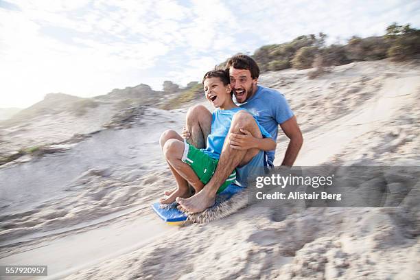 father and son playing on beach - rutsche stock-fotos und bilder