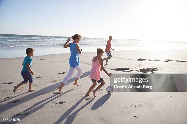family running on beach with a ball - beach ball soccer stock pictures, royalty-free photos & images