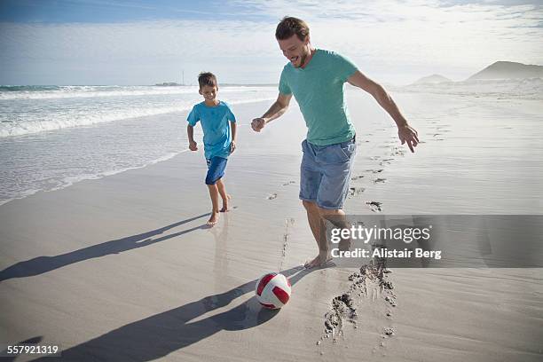 father and son playing soccer on beach - 8 ball stock-fotos und bilder