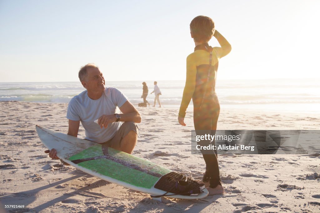 Man helping grandson with surf board
