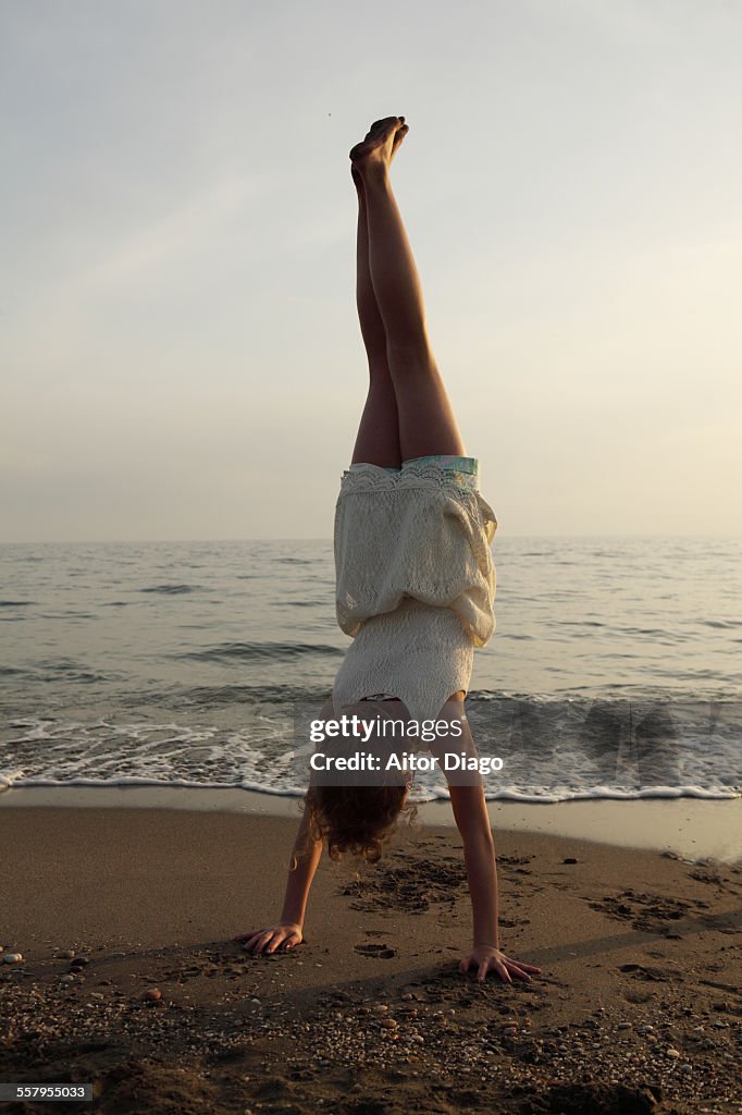 Girl doing a handstand at the beach