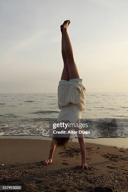 girl doing a handstand at the beach - girl in dress doing handstand stockfoto's en -beelden