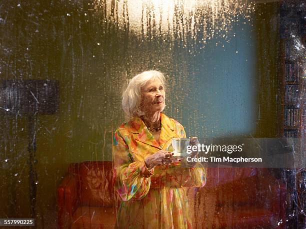 senior woman looks out of a window - looking through stock pictures, royalty-free photos & images