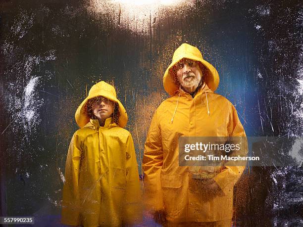 boy with grandfather stand wearing waterproofs - レインコート ストックフォトと画像