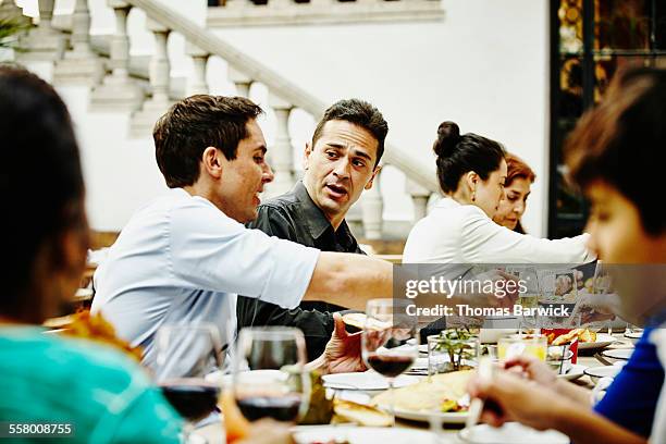 brothers in discussion during family dinner party - big family dinner stock pictures, royalty-free photos & images