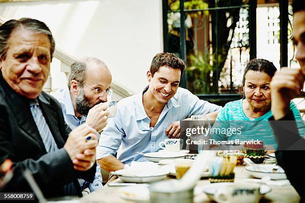 laughing man with family at dinner party - familientreffen stock-fotos und bilder