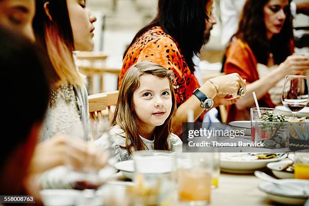 smiling girl sitting with family during dinner - family restaurant stock-fotos und bilder