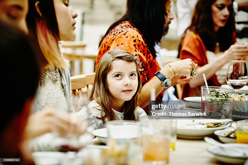 Smiling girl sitting with family during dinner