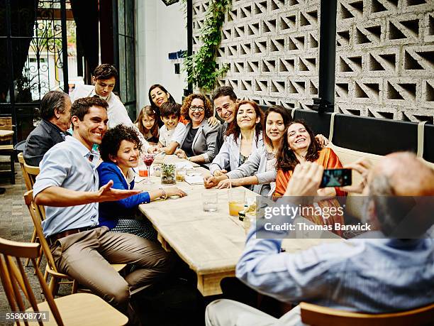 man taking family portrait in restaurant - thomas barwick meeting stock pictures, royalty-free photos & images