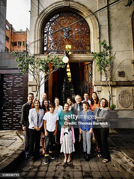 smiling family standing in front of restaurant - familia grande fotografías e imágenes de stock