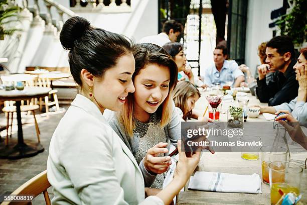 sisters looking at smartphone during family dinner - child foodie photos et images de collection