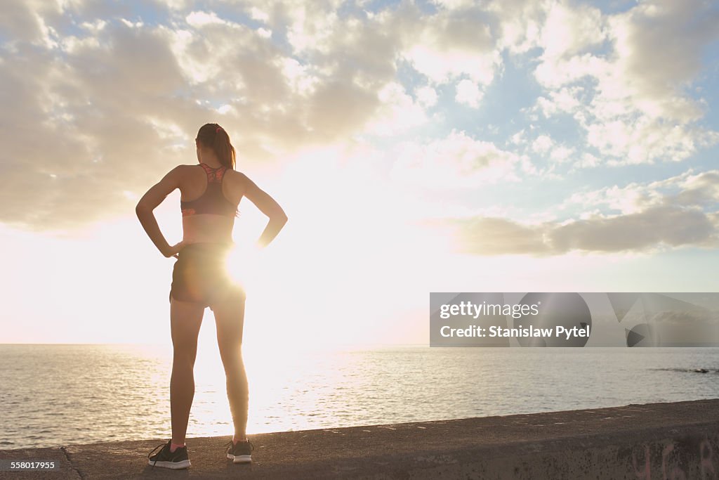 Girl resting during workout near ocean, sunset