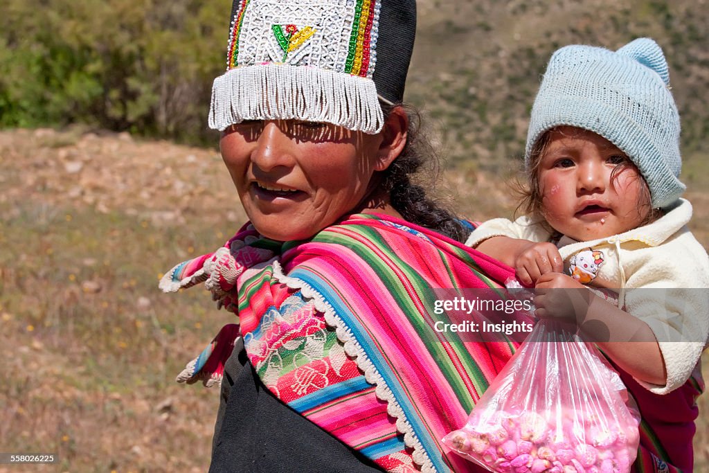 Tarabuco woman carrying girl, Jatun Yampara Indigenous Community, Chuquisaca Department, Bolivia