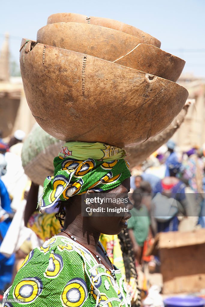 Woman carrying a calabash on her head at the Monday Market in Djenne, Mali