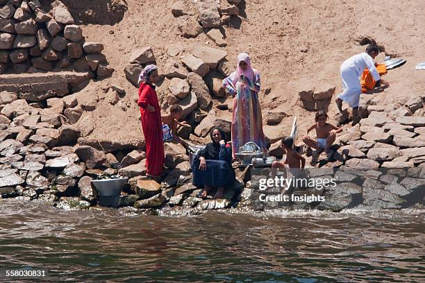 Women Washing Clothes By The Shore Of The Nile River Between Aswan And Edfu, Aswan, Egypt