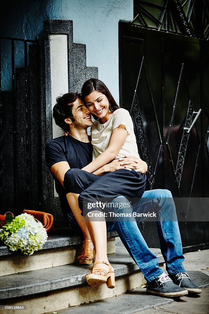 Smiling couple embracing on steps of building