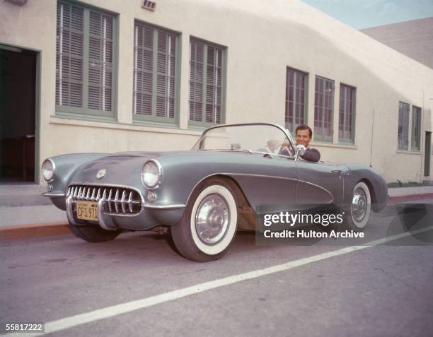 American singer Pat Boone sits in his 1956 or 1957 Chevrolet Corvette sports car and smiles, late 1950s.