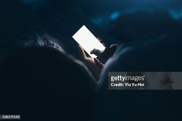 woman texting and reading on smartphone in bed - big tech foto e immagini stock