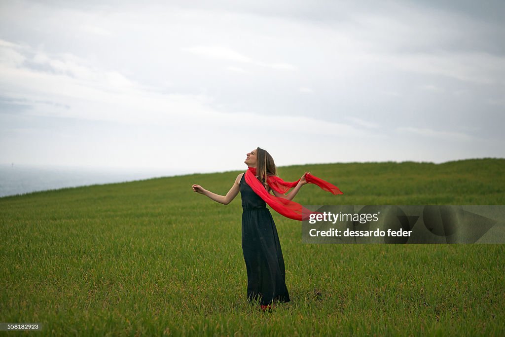 Woman with black dress and red pashmina on the gre