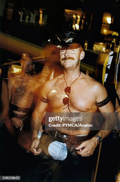 Half naked man wearing a leather chaps and hat.