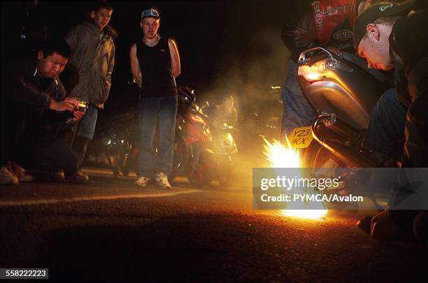 Group of teenagers watching a Catherine Wheel stunt, scooterists, Luton, UK 2004.