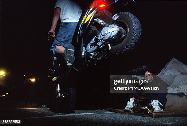 Teenager on a scooter doing an endo, while his friend watches, Luton, UK 2004.