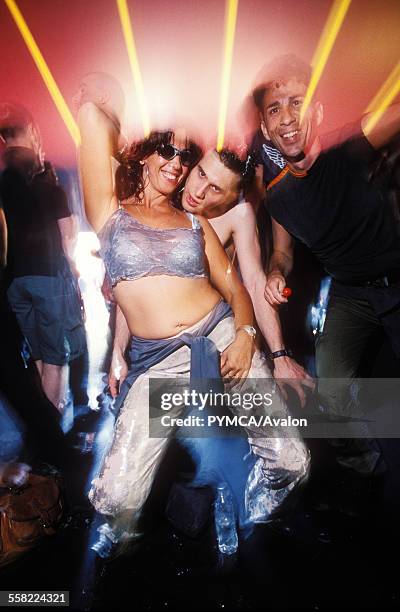 Three clubbers having a good time on the dancefloor of a club, UK 2000s.