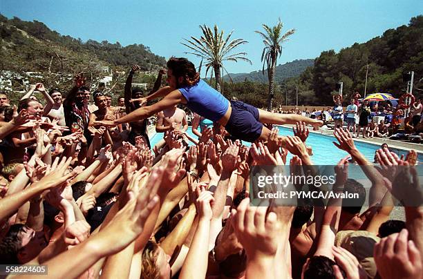 Holiday rep diving into a crowd of people, at a pool party, Club 18-30 Ibiza, 2001.