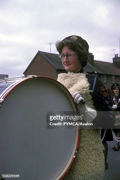 Woman playing a big bass drum at a GLB parade, Stowmarket, UK, 1963.
