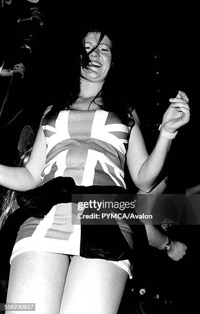 Girl dancing in club wearing union jack dress, smilling, Brighton, 1990s.