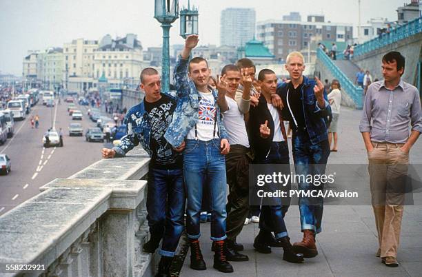 Skinheads gesturing while a pedestrian strolls past, Brighton, UK 1980's.