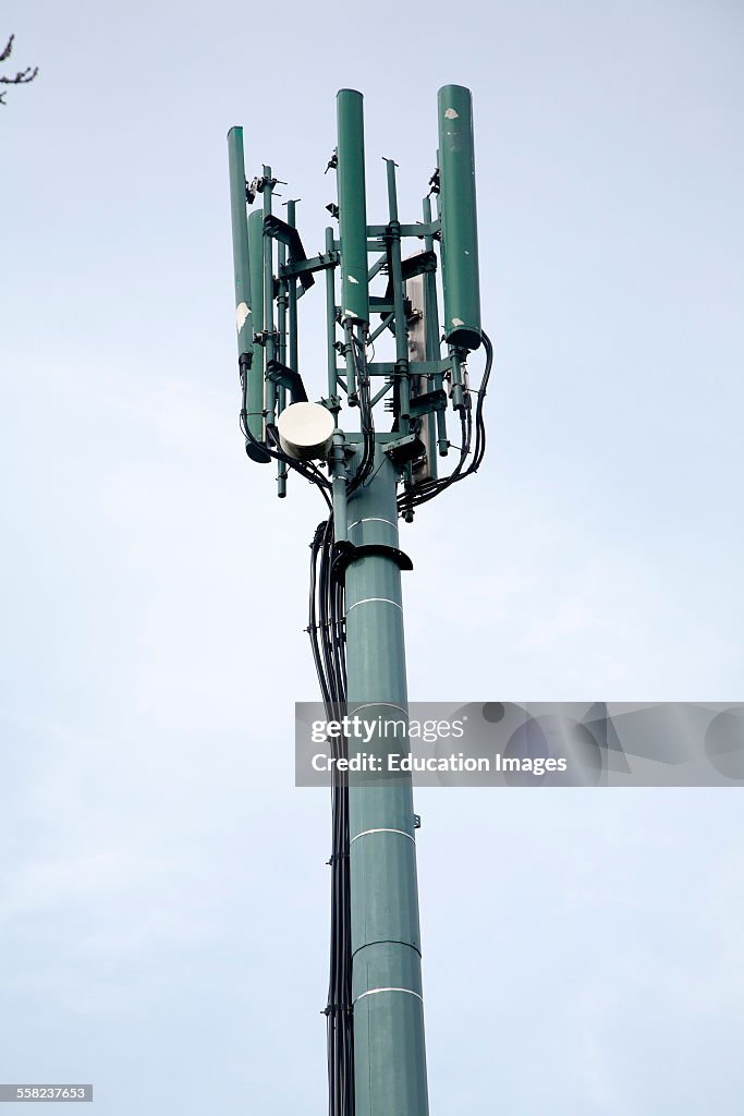 Mobile phone relay transmitter tower seen against blue cloudy sky, UK