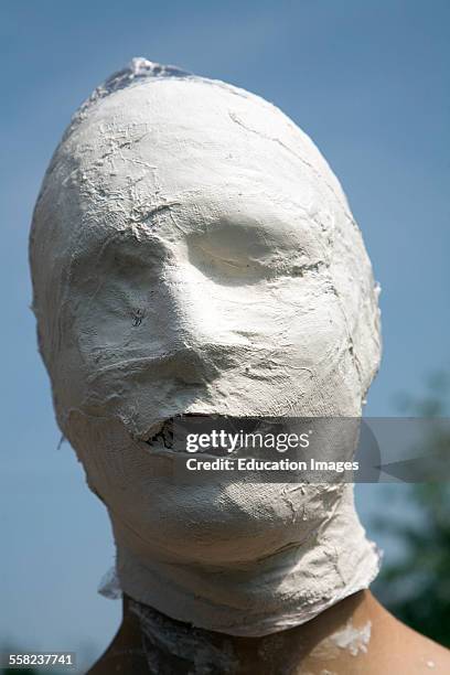 Young man's face covered in white bandage tape as art project