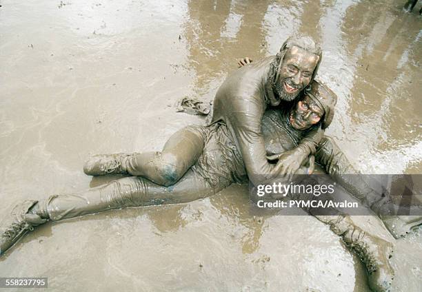 Mud covered couple engaging in a passionate clench at Glastonbury Festival UK 1998.