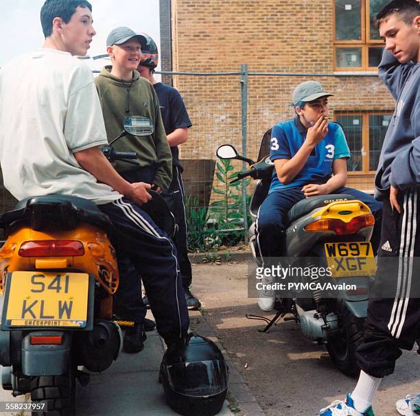 Group of boys sitting on motorbikes and smoking.