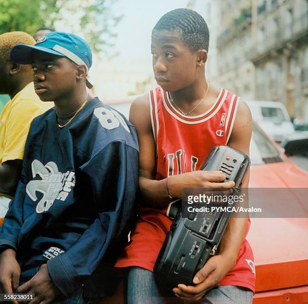 Teenage boys listening to music friom a stereo wearing American style football and basketball tops in Paris.