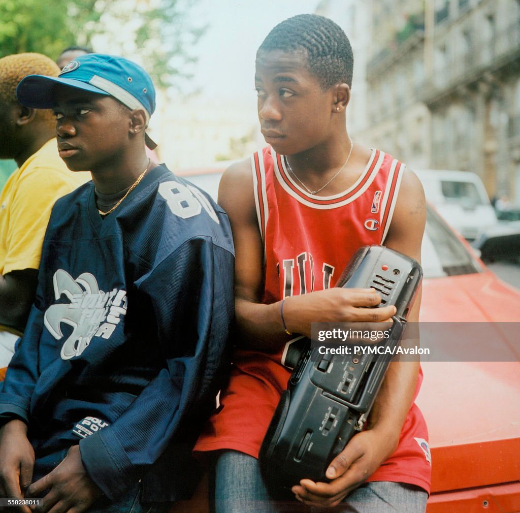 Teenage boys listening to music friom a stereo wearing American style football and basketball tops in Paris